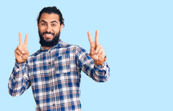 年轻的阿拉伯男子身穿休闲装 面带微笑地看着摄像机 手指头在做胜利的标志 第二点 — 图库照片
