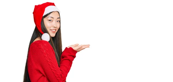 年轻的中国女人头戴圣诞礼帽 手拉手 张开手掌 展示复制的空间 笑容满面 喜形于色 — 图库照片