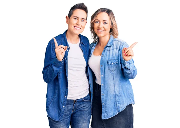 カジュアルな服を着ている女性のカップルは 異なる方向に指で自信を持って指して笑顔 広告のコピースペース — ストック写真
