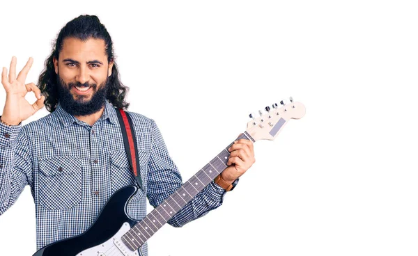 年轻的阿拉伯男子会弹奏电吉他 用手指做手势 微笑友善地表示出极好的象征 — 图库照片