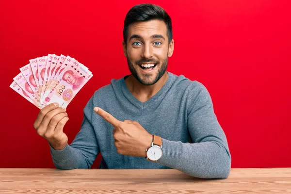 Hombre Hispano Guapo Sosteniendo Billetes Chinos Yuan Sonriendo Feliz Señalando —  Fotos de Stock