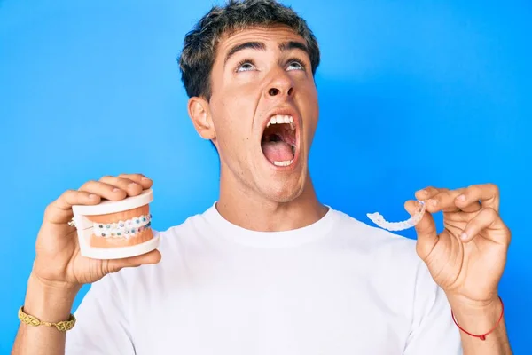 Jovem Homem Bonito Segurando Ortodontia Com Raiva Louco Gritando Frustrado — Fotografia de Stock