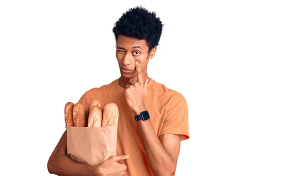 Νεαρός Αφροαμερικάνος Που Κρατάει Χάρτινη Σακούλα Ψωμί Δείχνοντας Μάτι Του — Φωτογραφία Αρχείου