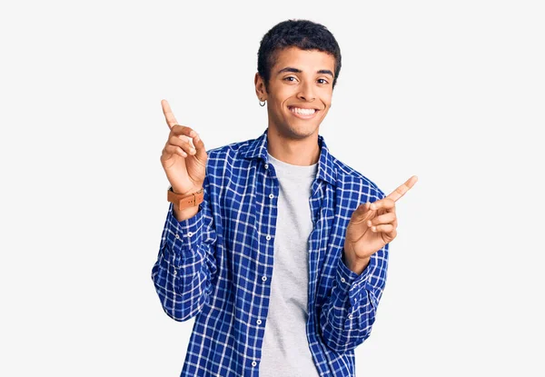 若いアフリカ系アメリカ人の男性は さまざまな方向に指で自信を持って笑みを浮かべてカジュアルな服を着ている 広告のコピースペース — ストック写真