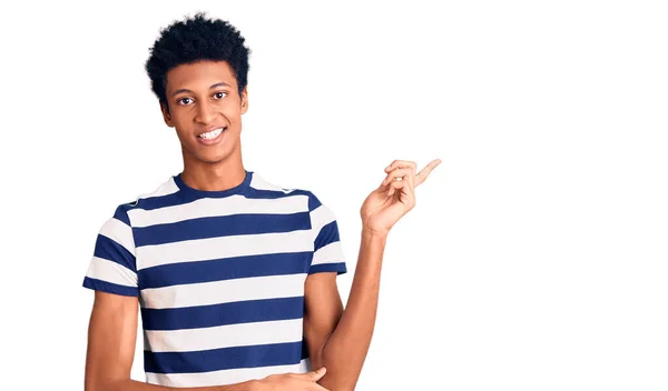カメラを見ている側に手と指で指して 顔に大きな笑顔でカジュアルな服を着て若いアフリカ系アメリカ人の男 — ストック写真