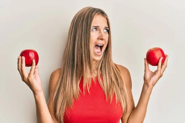 Mujer Rubia Joven Sosteniendo Manzanas Rojas Enojado Loco Gritando Frustrado — Foto de Stock