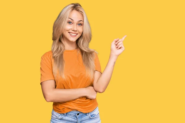Młoda Blondynka Luźnych Ubraniach Uśmiecha Się Szczęśliwy Wskazując Ręką Palcem — Zdjęcie stockowe