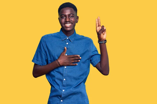 胸と指で手で身に着けて笑顔でカジュアルな服を着ている若いアフリカ系アメリカ人男性 忠誠の誓いを作る — ストック写真