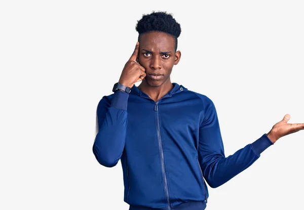 スポーツウェアを身に着けている若いアフリカ系アメリカ人の男性は コピースペースを示し 額に指を指すオープン手のひらに混乱し いらいらしています 考えてみてください — ストック写真