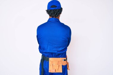 Kıvırcık saçlı ve ayı gibi giyinen yakışıklı genç adam arkasını dönüp çapraz kollarla bakıyor. 