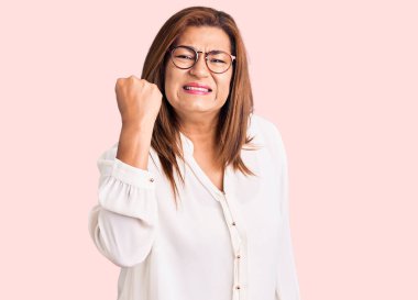 Orta yaşlı, gündelik kıyafetler giyen, gözlüklü kızgın, kızgın, sinirli ve öfkeliyken öfkeyle bağıran Latin bir kadın. öfke ve agresif konsept. 