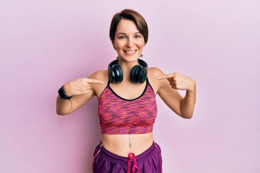 Kısa saçlı, spor giyimli, kulaklık takan, kendine güvenen, gülümseyen, kendini gururlu ve mutlu gösteren esmer bir kadın.. 