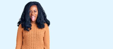 Güzel afro-amerikan kadın rahat bir süveter giyip dilini çıkarıp komik bir ifade takınıyor. duygu kavramı. 