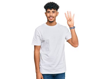 Gündelik beyaz tişört giyen genç Arap adam kendini beğenmiş ve mutlu bir şekilde gülümserken dört numarayı gösteriyor ve işaret ediyor.. 