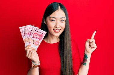 Genç Çinli kadın 10 Yuan 'lık Çin banknotları tutuyor. Gülümsüyor, mutlu bir şekilde elini ve parmağını kenarı gösteriyor. 