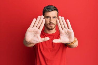 Yakışıklı beyaz adam, günlük kırmızı tişört giyiyor, el ve parmakları kullanarak çerçeve yapıyor, kamera bakış açısı var. 