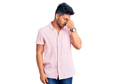 Yakışıklı Latin Amerikalı sıradan bir yaz tişörtü giymiş yorgun burnu ve gözleri ovuşturup yorgun ve başı ağrıyor. Stres ve hüsran kavramı. 