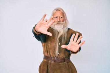 Gri saçlı, uzun sakallı, Viking kostümlü yaşlı bir adam. Avuç içi hareketlerini durduruyor. Öfkeli ve hayal kırıklığı dolu bir ifade takınıyor. 