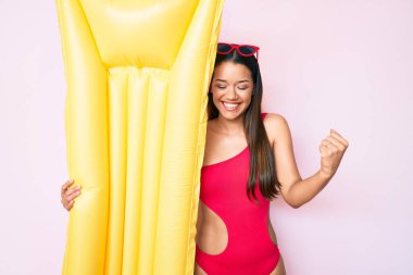 Mayolu genç ve güzel bir Latin kız ve elinde yüzen bir şamandıra var. Gururla bağırıyor, zaferi ve başarıyı kutluyor. Kaldırılmış kollarıyla çok heyecanlı. 