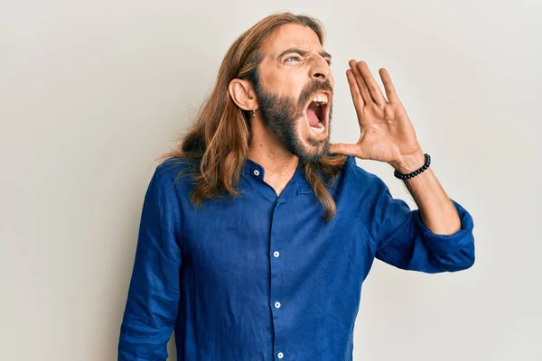 長い髪と髭を生やした魅力的な男がカジュアルな服を着て大声で叫び 口の中で手で横に大声で叫ぶ コミュニケーションの概念 — ストック写真