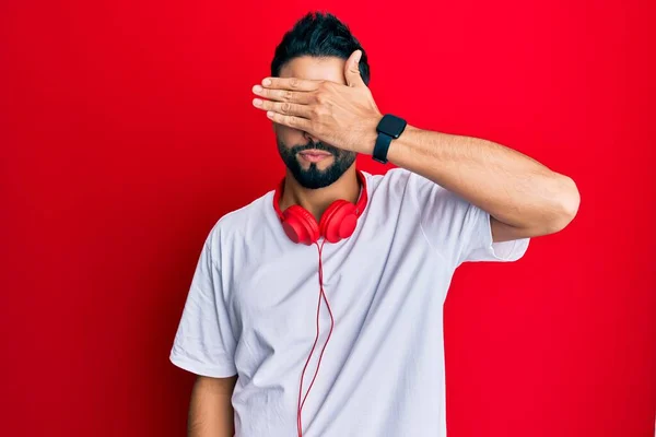 Νεαρός Γενειάδα Ακούει Μουσική Ακουστικά Που Καλύπτουν Μάτια Χέρι Δείχνοντας — Φωτογραφία Αρχείου
