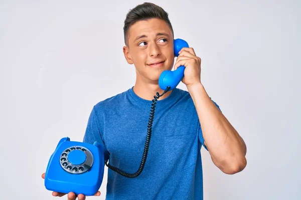 Jovem Hispânico Menino Segurando Telefone Vintage Sorrindo Olhando Para Lado — Fotografia de Stock