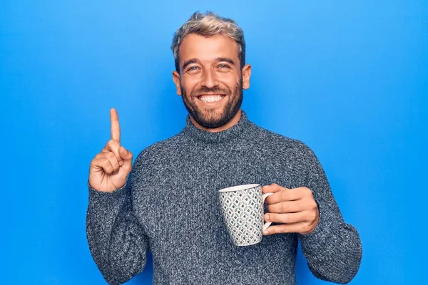 Młody Przystojny Blondyn Brodą Pijący Kawę Odizolowanym Niebieskim Tle Uśmiechający — Zdjęcie stockowe