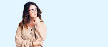 Güzel, genç, esmer bir kadın. Günlük kıyafetler ve gözlük takıyor. Elleri çenesinde soru sormayı düşünüyor. Düşünceli bir yüzle gülümsüyor. şüphe kavramı. 