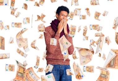 Kış süveteri ve eşarp giyen genç Afrikalı Amerikalı adam kıkırdıyor ve gülüyor. Ağzı ellerle, dedikoduyla ve skandalla örtüyor.