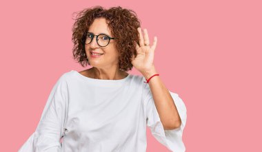 Güzel, orta yaşlı yetişkin bir kadın. Günlük kıyafetler ve gözlük takıyor. Kulaktan kulağa gülümsüyor, dedikodu ve dedikoduları dinliyor. Sağırlık kavramı. 