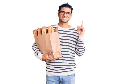 Elinde ekmek dolu kağıt torba tutan İspanyol yakışıklı genç bir adam bir fikre şaşırmış ya da mutlu yüzle işaret eden bir soru sormuş. 