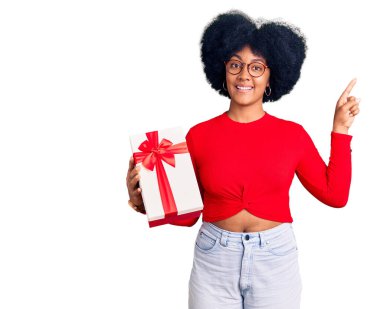 Genç Afro-Amerikalı kız elinde kocaman bir gülümseme ile kameraya el ile işaret ederek hediyesini tutuyor.. 