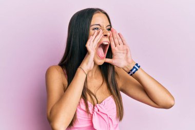 Kolsuz tişörtlü, gündelik giyinen genç İspanyol kadın elleri ağzında bağırarak bağırıyor. 