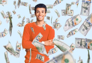 Sıradan kıyafetler giyen, kollarını kavuşturup kameraya gülümseyen genç bir Afrikalı Amerikalı. pozitif kişi.