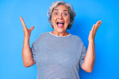 Kıdemli İspanyol beyaz saçlı kadın zaferi mutlu bir gülümsemeyle ve ellerini kaldırarak kutluyor. 