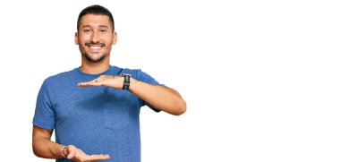 Dövmeleri olan, sıradan kıyafetler giyen, elleri büyük ve büyük beden işareti olan yakışıklı bir adam. Kameraya bakıp gülümsüyor. ölçüm kavramı. 