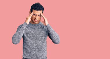 İspanyol asıllı yakışıklı genç adam stres yüzünden kafasında ağrı için elleri kafasında sıradan bir süveter giyiyor. migren ağrısı. 