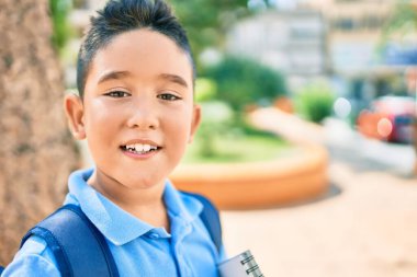 Şehrin caddesinde mutlu gülümseyen sevimli öğrenci çocuk..