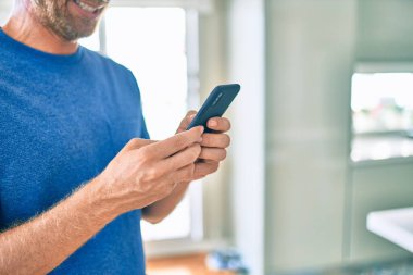 Genç İrlandalı adam mutlu bir şekilde gülümsüyor ve akıllı telefon kullanıyor..