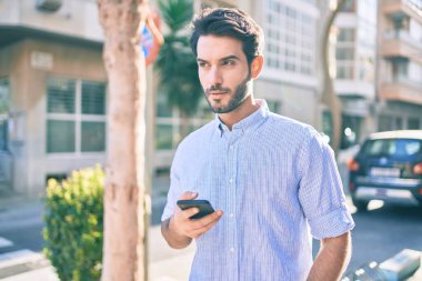 Şehirde akıllı telefon kullanan ciddi bir suratı olan genç bir İspanyol..