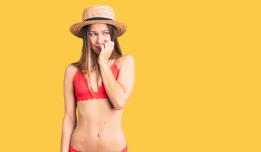 Güzel esmer, bikini giyen, gergin ve gergin görünen, elleri ağızdan tırnak yiyen bir kadın. anksiyete. 