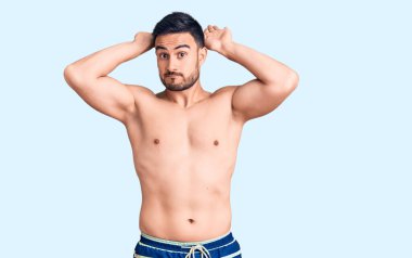 Mayo giyen, tavşan kulağı hareketi yapan genç yakışıklı bir adam avuçlarıyla alaycı ve şüpheci görünüyor. Paskalya tavşanı konsepti. 