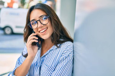 Genç İspanyol iş kadını gülümsüyor. Şehirdeki akıllı telefondan mutlu bir şekilde konuşuyor..