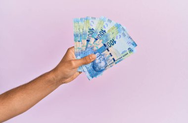 İspanyol el, 100 Güney Afrika bankasını soyutlanmış pembe arka planda tutuyor..