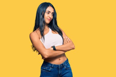 Güzel İspanyol kadın gündelik kıyafetler giyip kollarını kavuşturmuş ve kendinden emin bir şekilde yan tarafa bakıyor. 