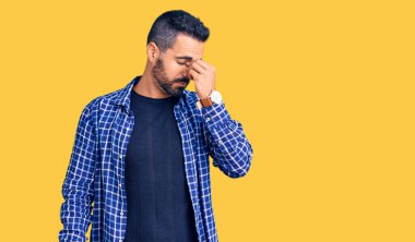 Günlük kıyafetler giyen genç İspanyol adam yorgun burnu ve gözleri ovuşturup yorgun ve baş ağrısı çekiyor. Stres ve hüsran kavramı. 