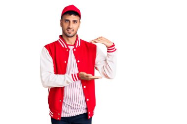 Beyzbol forması giyen, elleri büyük ve büyük boy işareti gösteren İspanyol bir adam. Ölçüm sembolü. Kameraya bakıp gülümsüyor. ölçüm kavramı. 