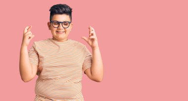 Günlük kıyafetler ve gözlük takan küçük çocuk umut ve gözlerin kapalı bir şekilde gülümseyerek bana işaret etti. Şans ve batıl inançlar. 