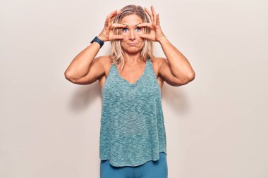 Orta yaşlı beyaz kadın spor kıyafetleri giyiyor. Gözlerini parmaklarıyla açmaya çalışıyor. Sabah yorgunluğu yüzünden uykulu ve yorgun. 