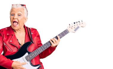 Son sınıf güzeli, mavi gözlü, gri saçlı, modern görünümlü, elektro gitar çalan, dilini dışarı çıkaran, komik bir ifadeyle mutlu bir kadın. duygu kavramı. 